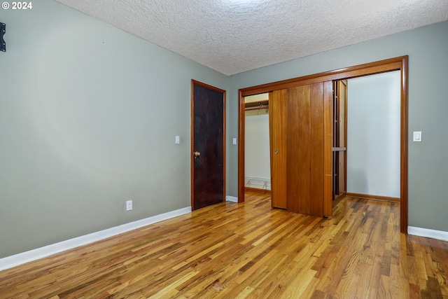 unfurnished bedroom with light wood-type flooring, a textured ceiling, and a closet