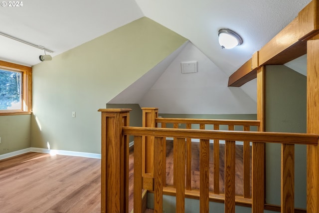 stairway with hardwood / wood-style floors and vaulted ceiling