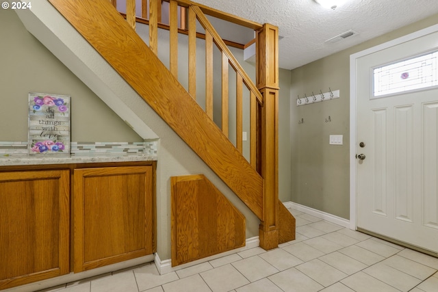 entrance foyer with light tile patterned floors and a textured ceiling