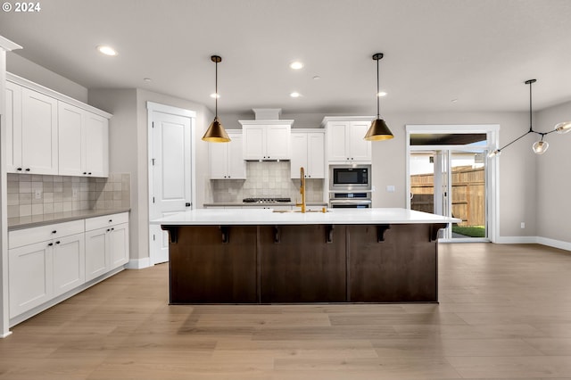 kitchen with a kitchen island with sink, white cabinetry, and stainless steel appliances