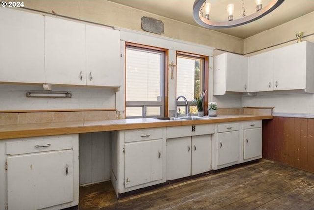 kitchen with wood walls, dark hardwood / wood-style floors, white cabinets, and sink