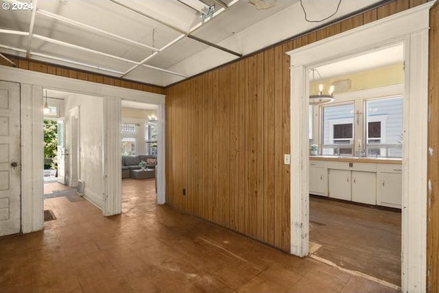 hall featuring an inviting chandelier, wood walls, and a wealth of natural light