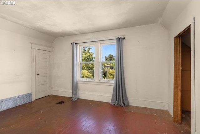 spare room featuring lofted ceiling and dark hardwood / wood-style floors