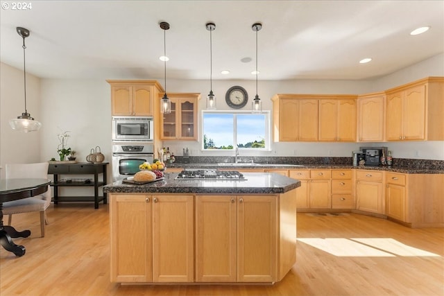 kitchen with decorative light fixtures, stainless steel appliances, light hardwood / wood-style floors, and light brown cabinets