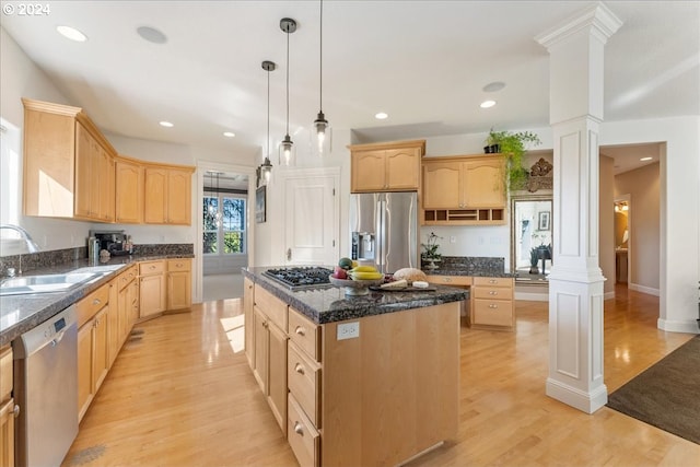 kitchen with appliances with stainless steel finishes, sink, a kitchen island, and ornate columns