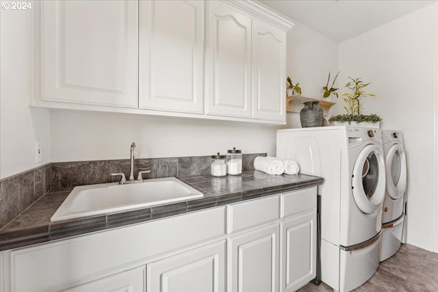 laundry area with washing machine and clothes dryer, cabinets, and sink