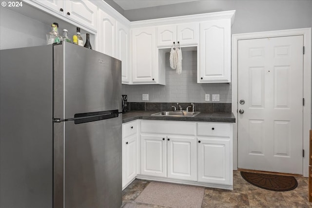 kitchen featuring stainless steel refrigerator, white cabinetry, sink, and tasteful backsplash