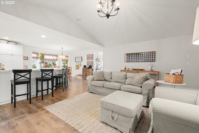 living room with lofted ceiling, a notable chandelier, light wood-style flooring, and recessed lighting