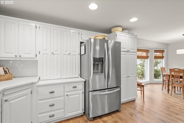 kitchen with light countertops, white cabinets, stainless steel fridge, and light wood-style flooring