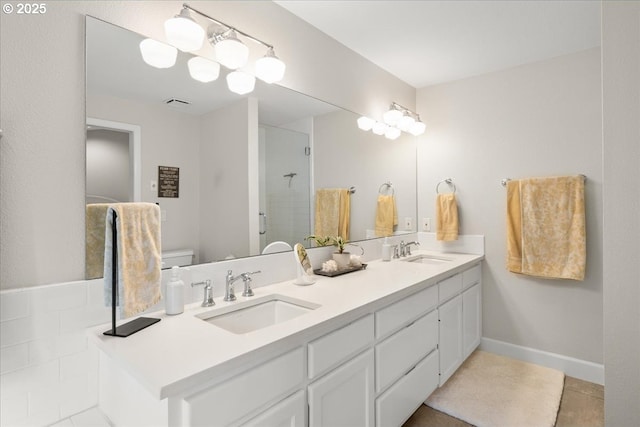 full bathroom featuring double vanity, a shower stall, baseboards, and a sink