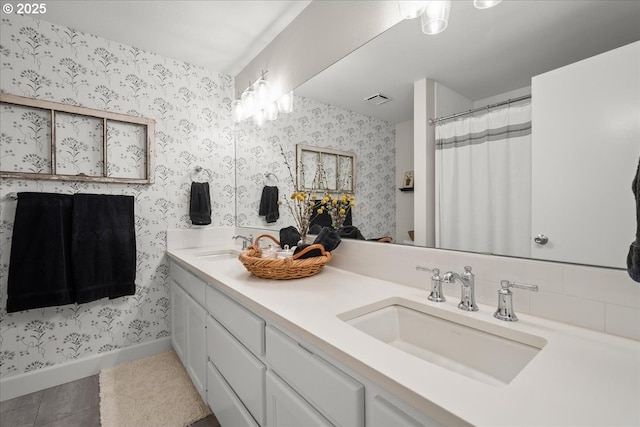 bathroom featuring double vanity, visible vents, a sink, baseboards, and wallpapered walls