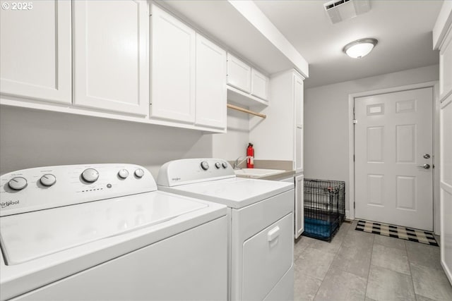 clothes washing area with visible vents, a sink, washing machine and dryer, and cabinet space