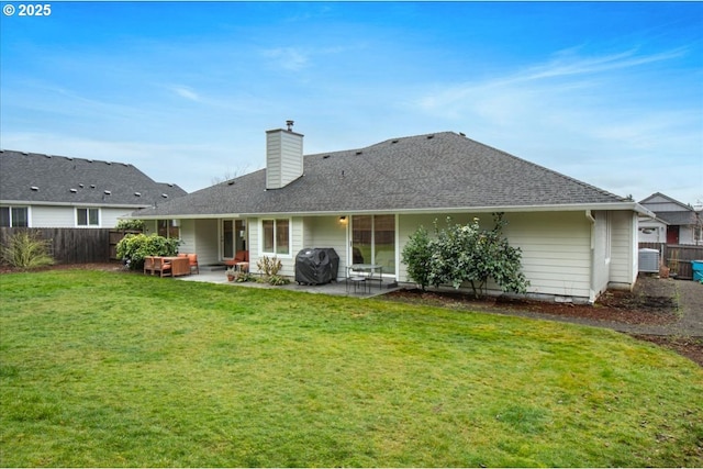 rear view of house with a patio, a shingled roof, fence, a lawn, and a chimney