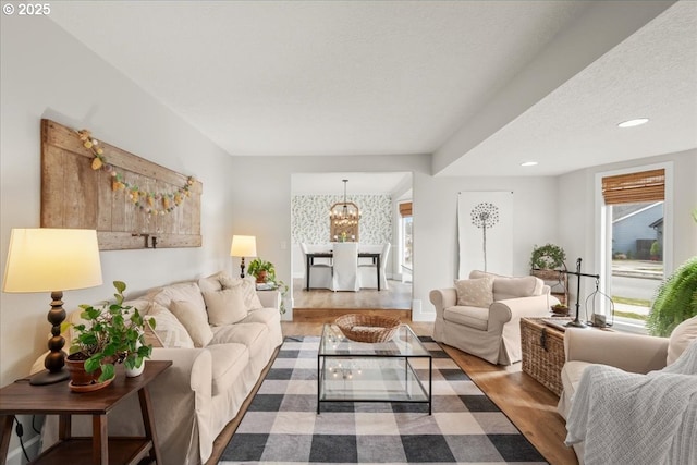 living room featuring baseboards, dark wood-style flooring, a textured ceiling, a notable chandelier, and recessed lighting