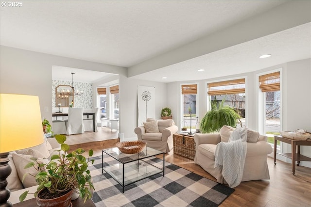 living area with a textured ceiling, wood finished floors, a wealth of natural light, and a chandelier