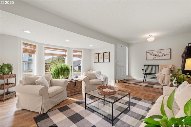 living room featuring light wood-type flooring, a textured ceiling, baseboards, and recessed lighting