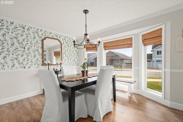 dining area featuring wallpapered walls, an inviting chandelier, crown molding, a textured ceiling, and light wood-style floors