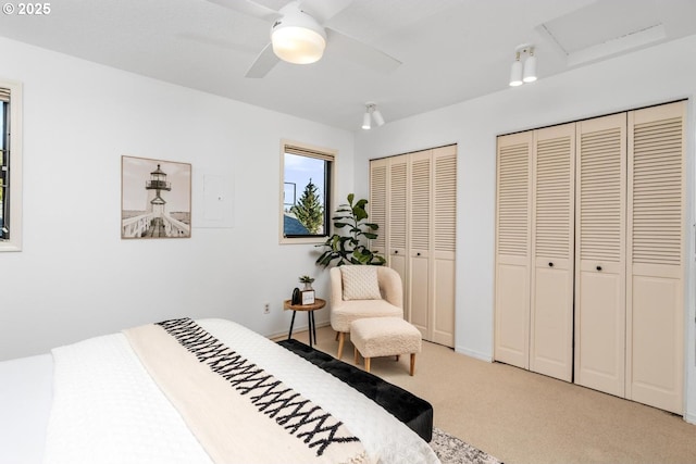 bedroom with multiple closets, ceiling fan, and light carpet