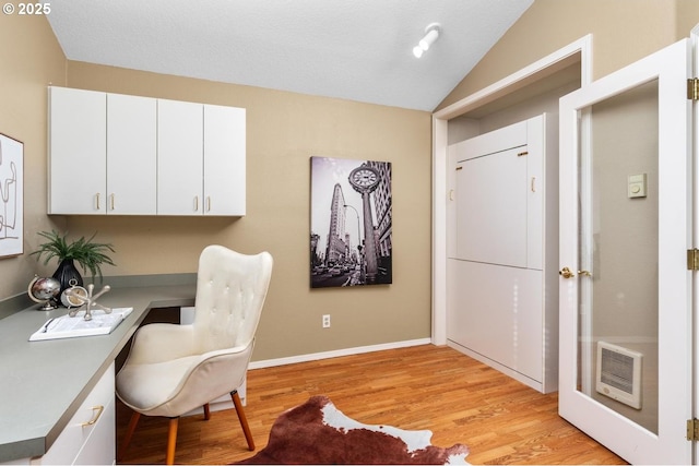 office area featuring light wood-type flooring, heating unit, and lofted ceiling