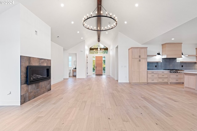 kitchen featuring stainless steel gas stovetop, light brown cabinets, light hardwood / wood-style floors, and a tiled fireplace