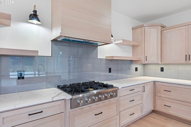 kitchen with light brown cabinetry, premium range hood, tasteful backsplash, light hardwood / wood-style floors, and stainless steel gas stovetop