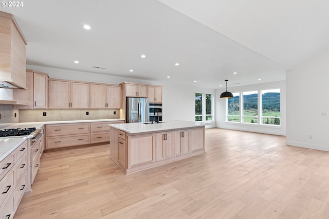 kitchen featuring light brown cabinets, a kitchen island with sink, sink, light hardwood / wood-style flooring, and stainless steel appliances