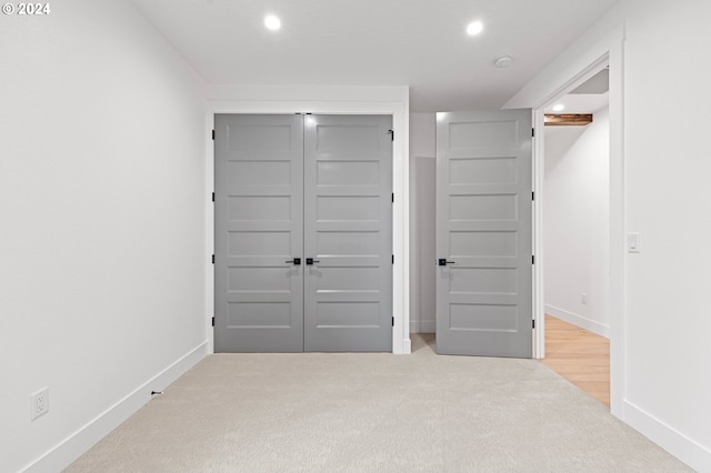 unfurnished bedroom featuring a closet and light colored carpet