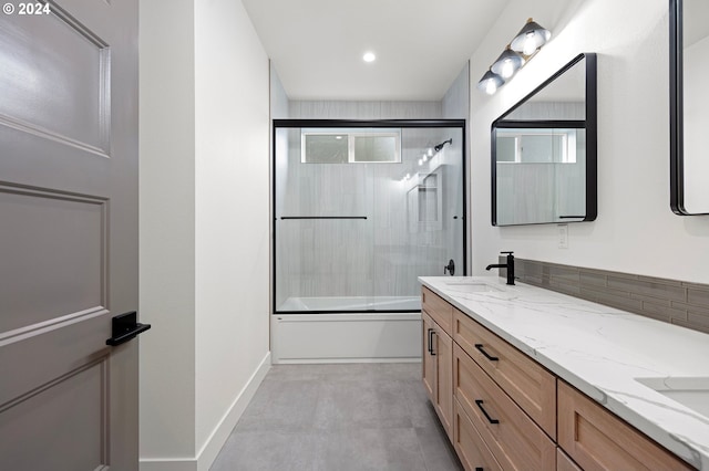 bathroom featuring vanity, combined bath / shower with glass door, and backsplash