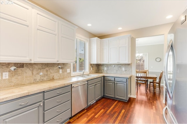 kitchen with white cabinetry, appliances with stainless steel finishes, tasteful backsplash, dark hardwood / wood-style floors, and gray cabinets