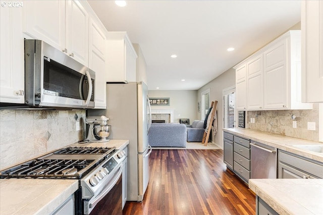 kitchen featuring stainless steel appliances, white cabinetry, tasteful backsplash, tile counters, and dark hardwood / wood-style flooring