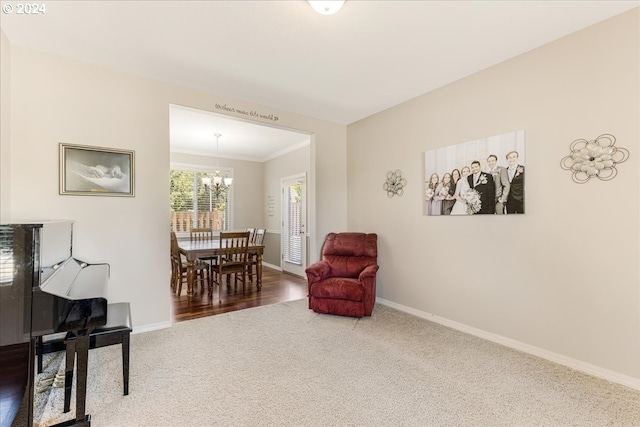 sitting room featuring carpet floors, crown molding, and an inviting chandelier