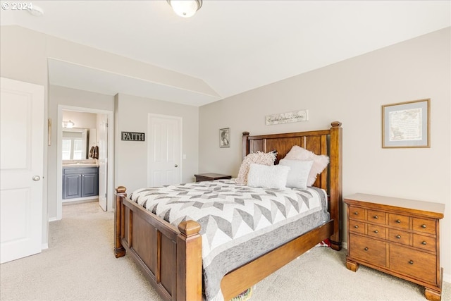 bedroom featuring ensuite bathroom, light carpet, and vaulted ceiling