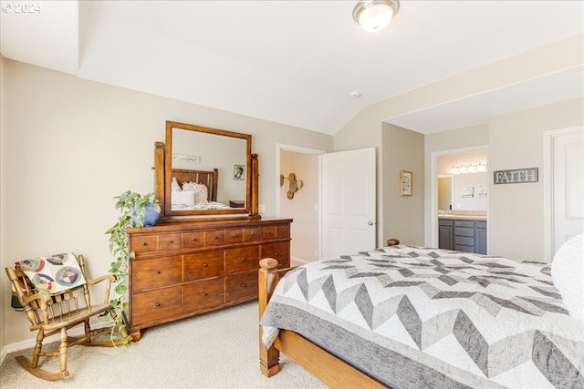 bedroom with vaulted ceiling, light colored carpet, and ensuite bathroom