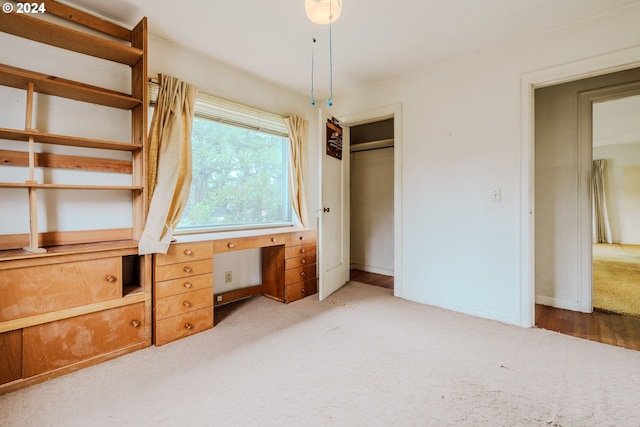 unfurnished bedroom featuring carpet floors, a closet, and built in desk