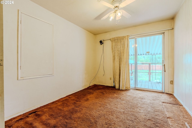 empty room featuring carpet flooring, ceiling fan, and wooden walls