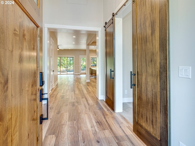 hall with wood ceiling, a barn door, and light hardwood / wood-style floors