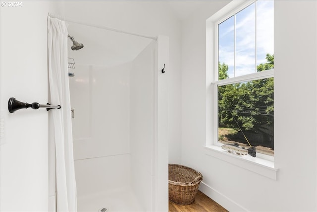 bathroom with a shower, a healthy amount of sunlight, and wood-type flooring