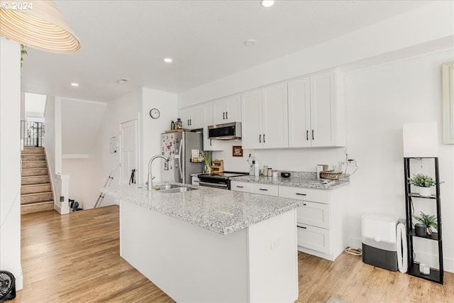 kitchen with light stone countertops, light wood-type flooring, appliances with stainless steel finishes, and white cabinetry