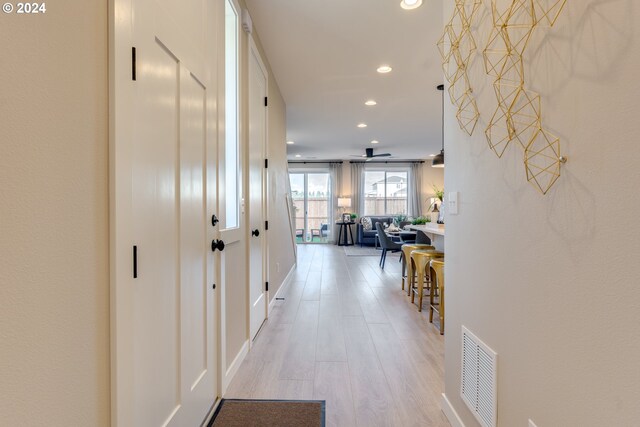 hallway with recessed lighting, visible vents, and light wood-style floors