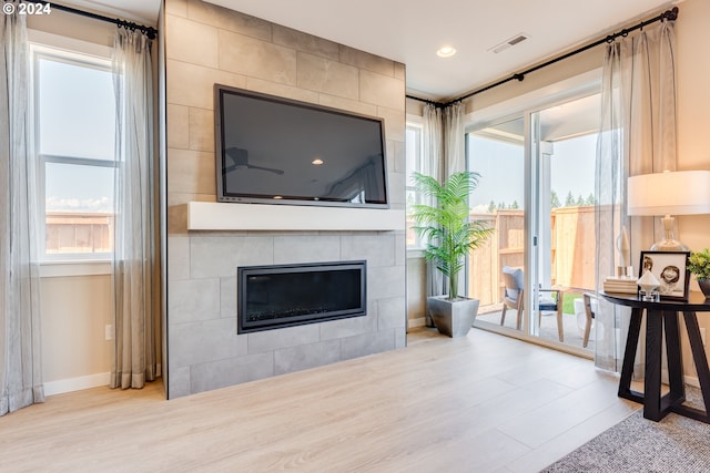 living room featuring visible vents, baseboards, a healthy amount of sunlight, and wood finished floors