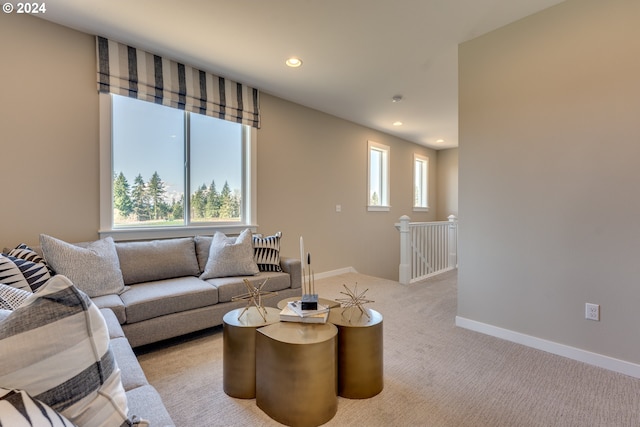 living area featuring a wealth of natural light, baseboards, and light carpet