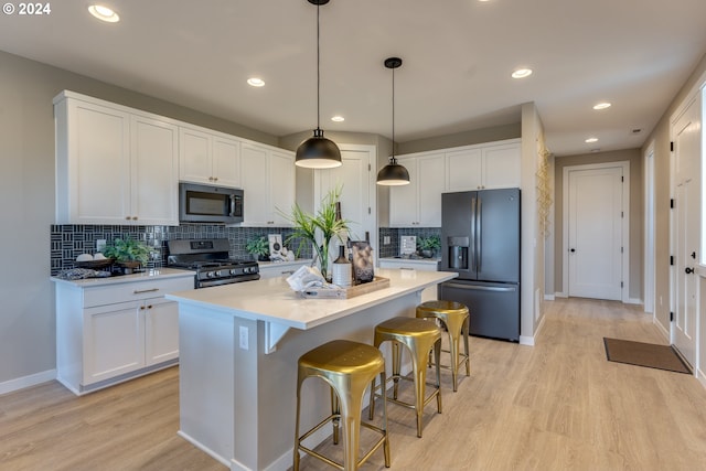 kitchen with light wood finished floors, stainless steel range with gas stovetop, white cabinets, refrigerator with ice dispenser, and a center island