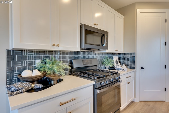 kitchen with light wood-type flooring, appliances with stainless steel finishes, and white cabinets