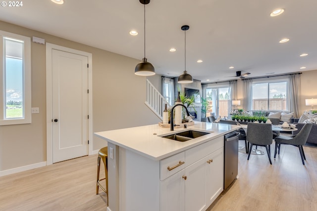 kitchen featuring light wood finished floors, open floor plan, dishwasher, and a sink