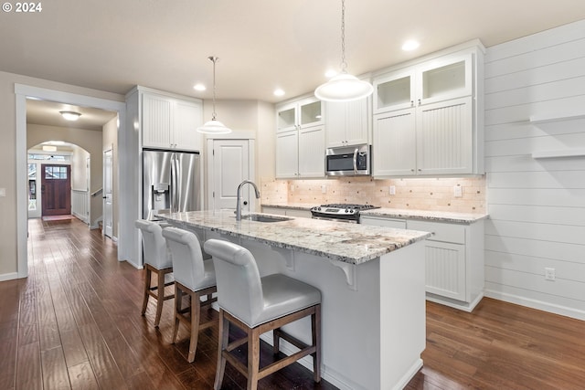 kitchen with appliances with stainless steel finishes, dark wood-type flooring, sink, a center island with sink, and white cabinetry