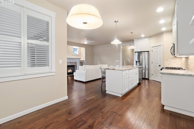 kitchen with white cabinetry, a kitchen island with sink, decorative light fixtures, and appliances with stainless steel finishes