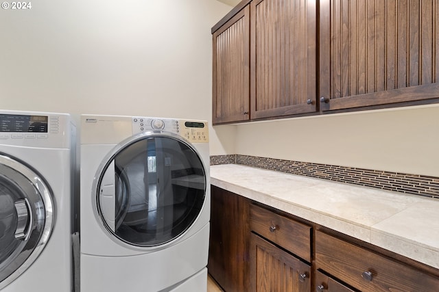 clothes washing area with washing machine and clothes dryer and cabinets