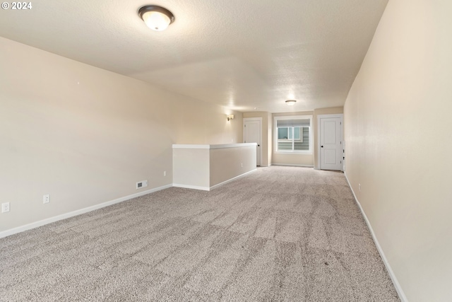 carpeted empty room featuring a textured ceiling