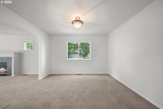 unfurnished room with carpet flooring and a tiled fireplace