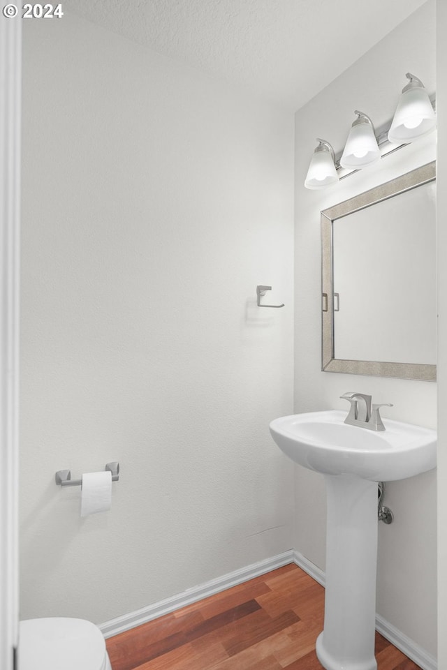 bathroom with a textured ceiling, toilet, and hardwood / wood-style flooring